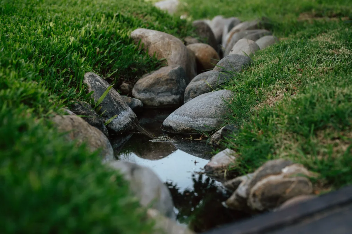 Shallow grassed swale channeling water across a sloped backyard