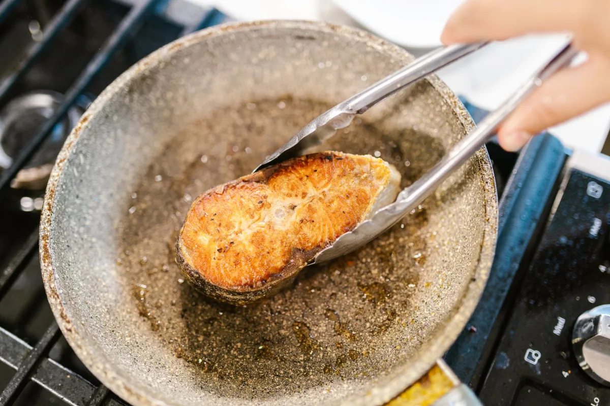 Cooled bacon grease pooled in a frying pan next to a kitchen sink
