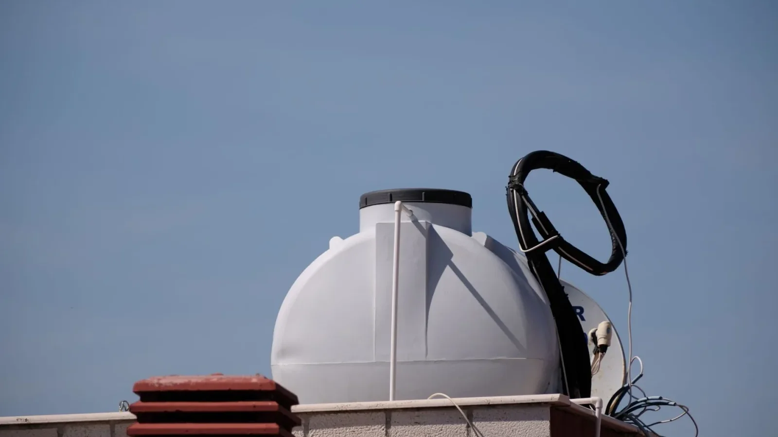 Concrete septic tank being lowered into a dug hole in a residential yard