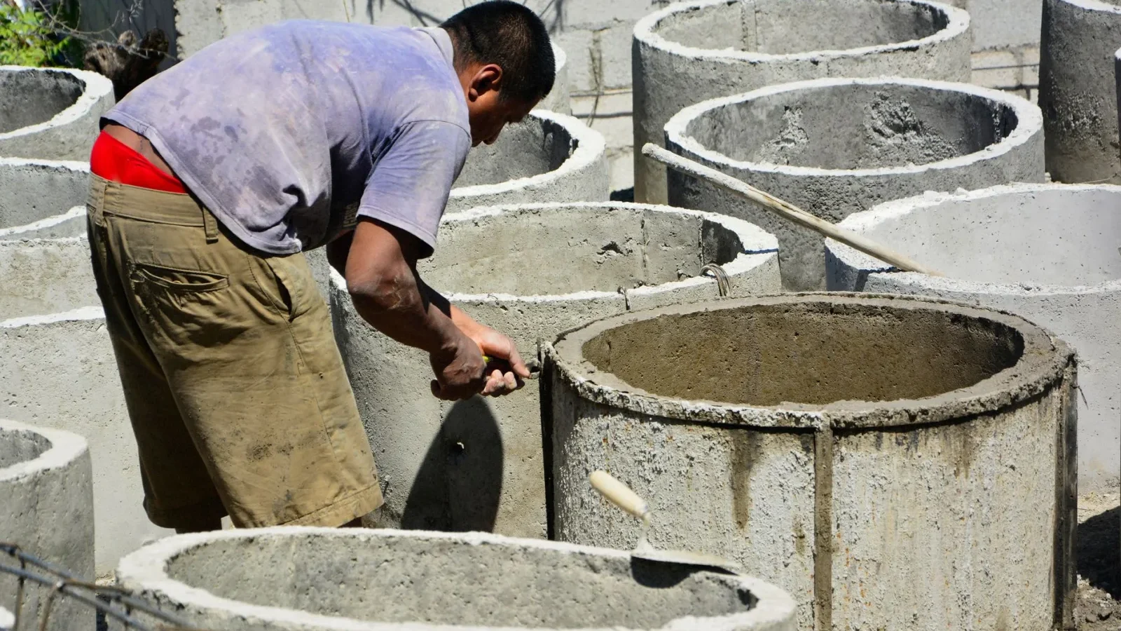 Contractor working on an open septic tank during a repair in a residential yard