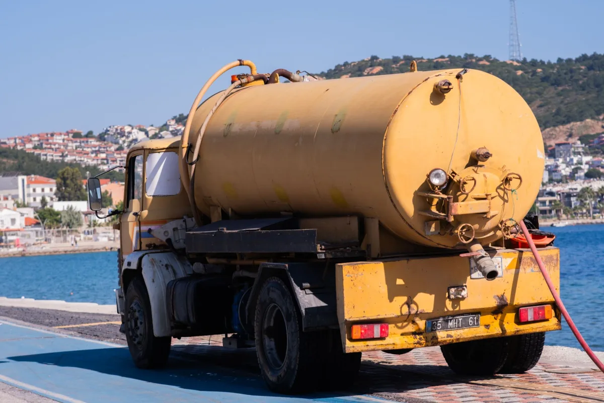 Septic pumping truck servicing a residential tank in a yard