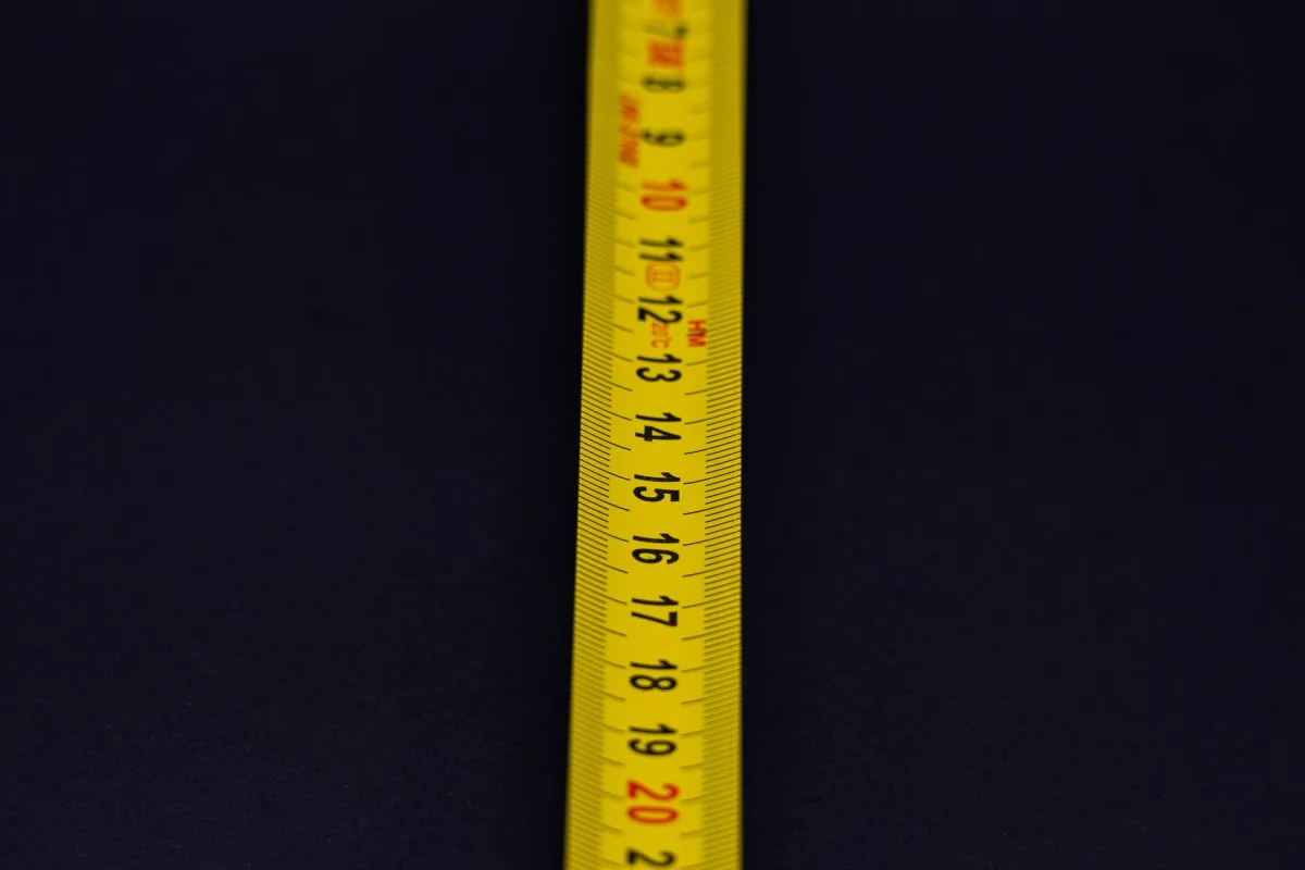 Person measuring a distance across a backyard with a tape measure
