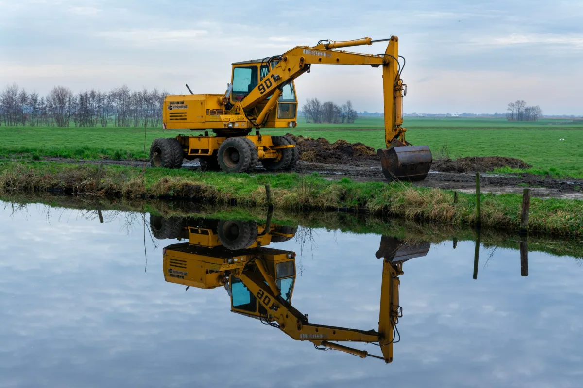 Excavator digging a trench for a replacement septic drain field