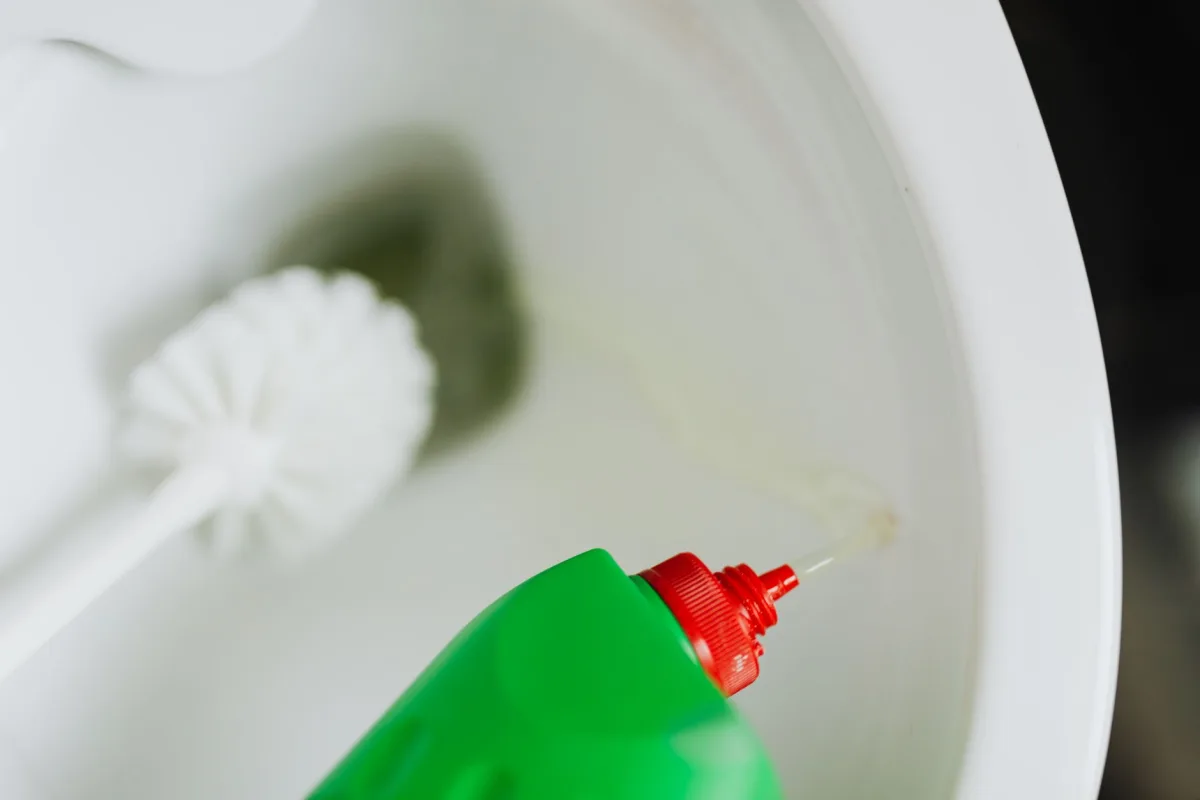 Bottle of enzyme drain cleaner being poured into a kitchen sink drain
