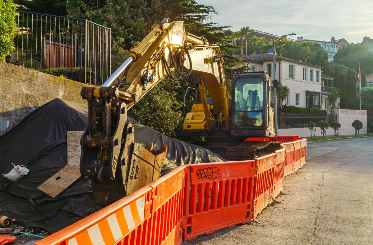 An excavator digging a trench in a backyard for a septic drain field