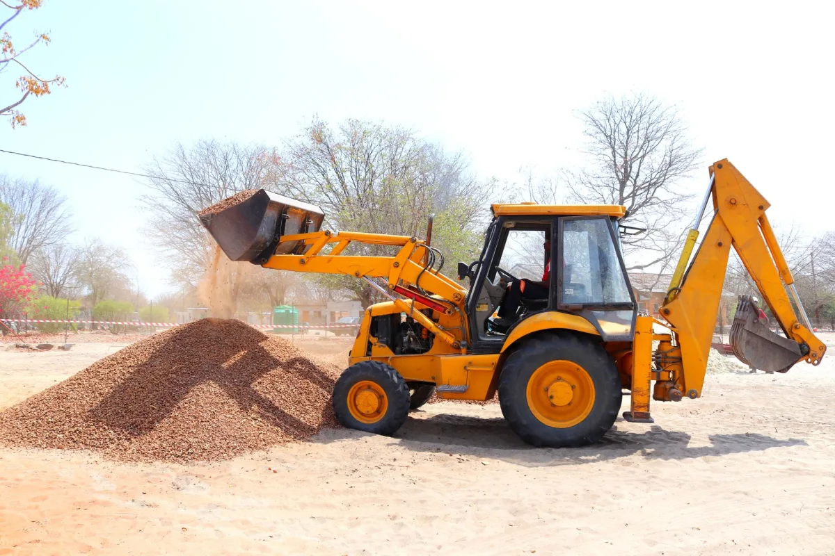Backhoe digging out an old septic tank in a residential backyard